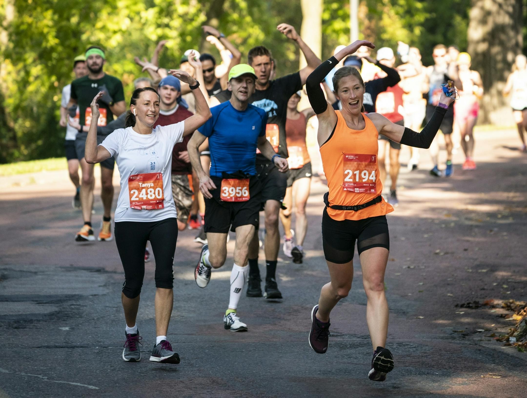 Runners including Tanya Steffl, in white, and Kirsten Van Hoorn, in orange, used their arms to sing along with the song YMCA as they past a party with a DJ and bouncy houses near mile 10.