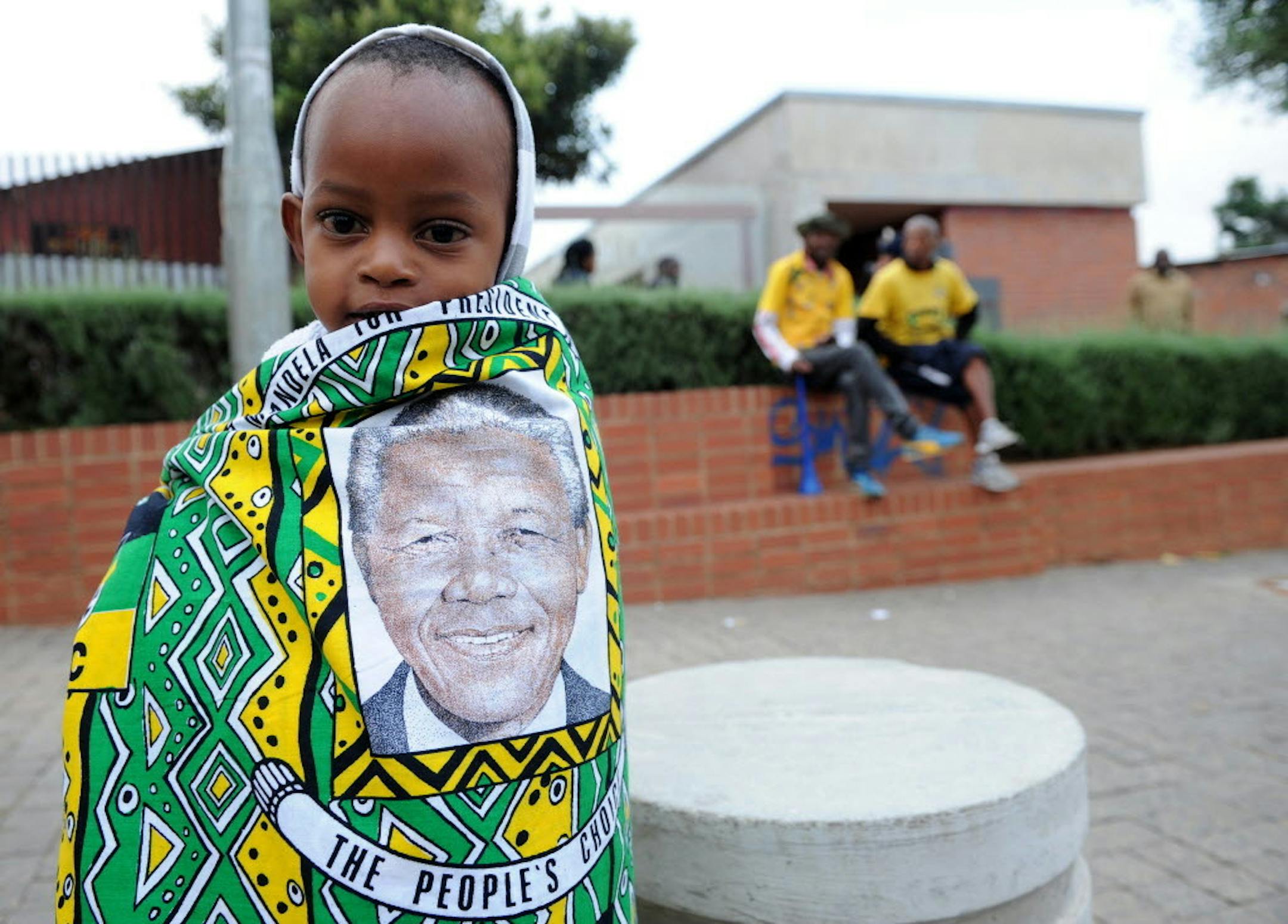 A child draped in a cloth with the image of former South African president Nelson Mandela, stands outside his former home, now museum, in Soweto, South Africa, Friday, Dec. 6, 2013.
