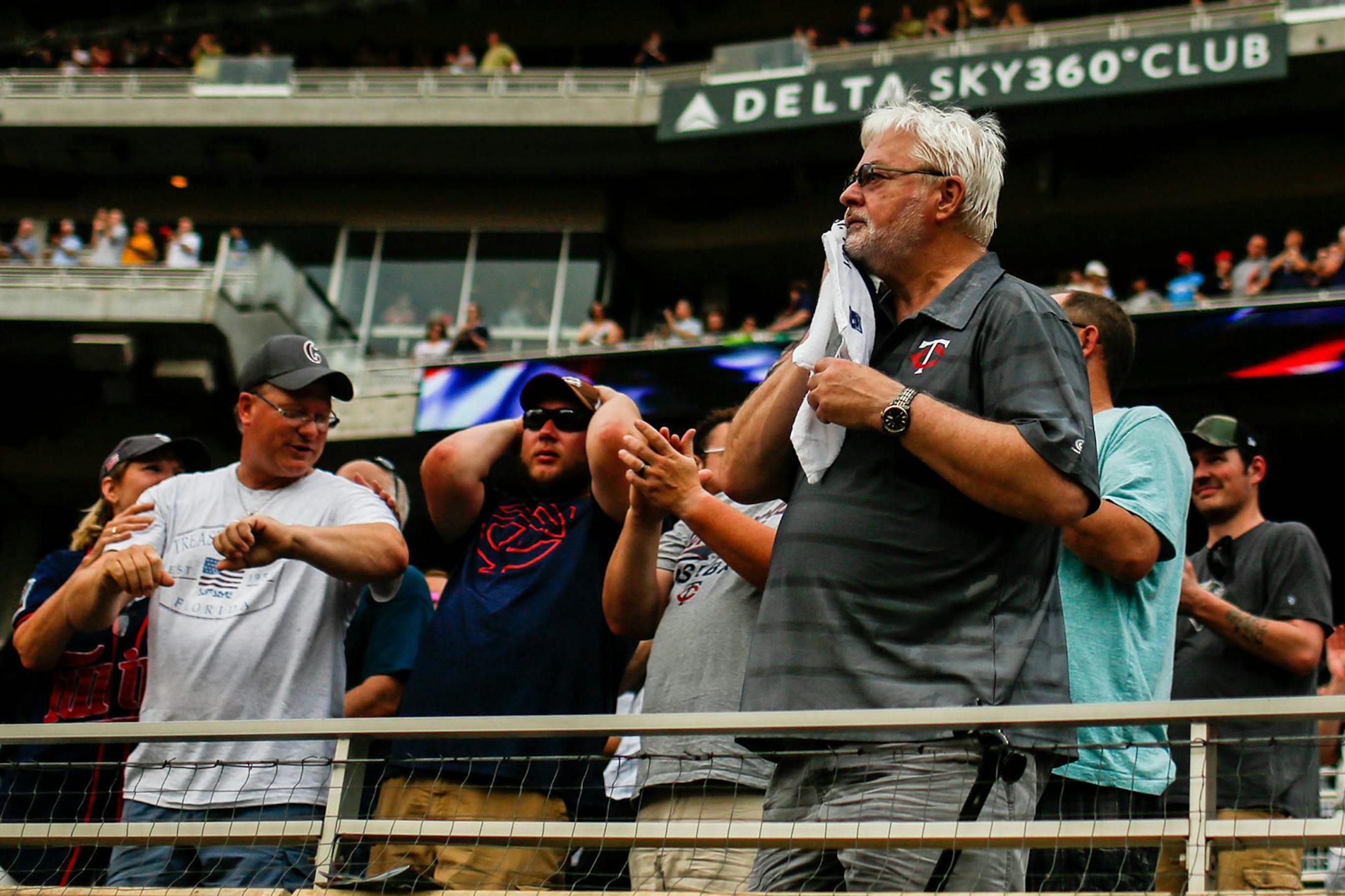 A Minnesota Twins fan wipes sweat off of his face with a towel after standing for the national anthem before the game in the heat and humidity on Friday, July 19, 2019.