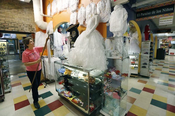 Olga Beltran, seen hanging up first communion dresses at Mercado Central marketplace, said sales at her store have dropped in the last six months.