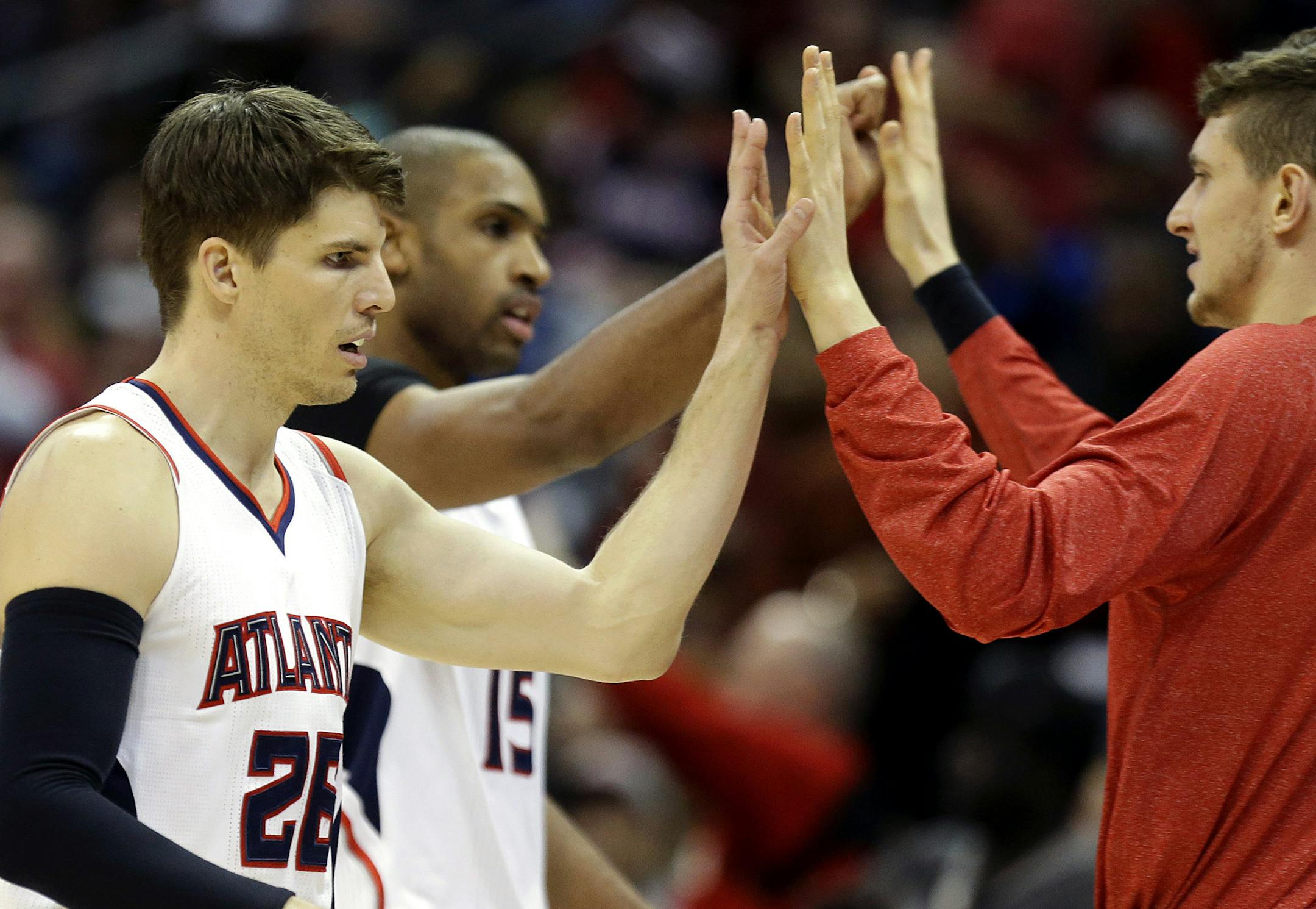 Atlanta Hawks' Kyle Korver, left, high-fives teammate Mike Muscala, right, along with Al Horford, rear, after Korver hit a 3-point basket in the final minutes of an NBA basketball game against the Minnesota Timberwolves, Sunday, Jan. 25, 2015, in Atlanta. The Hawks beat the Timberwolves 112-100 to win their 16th game in a row. (AP Photo/David Goldman)