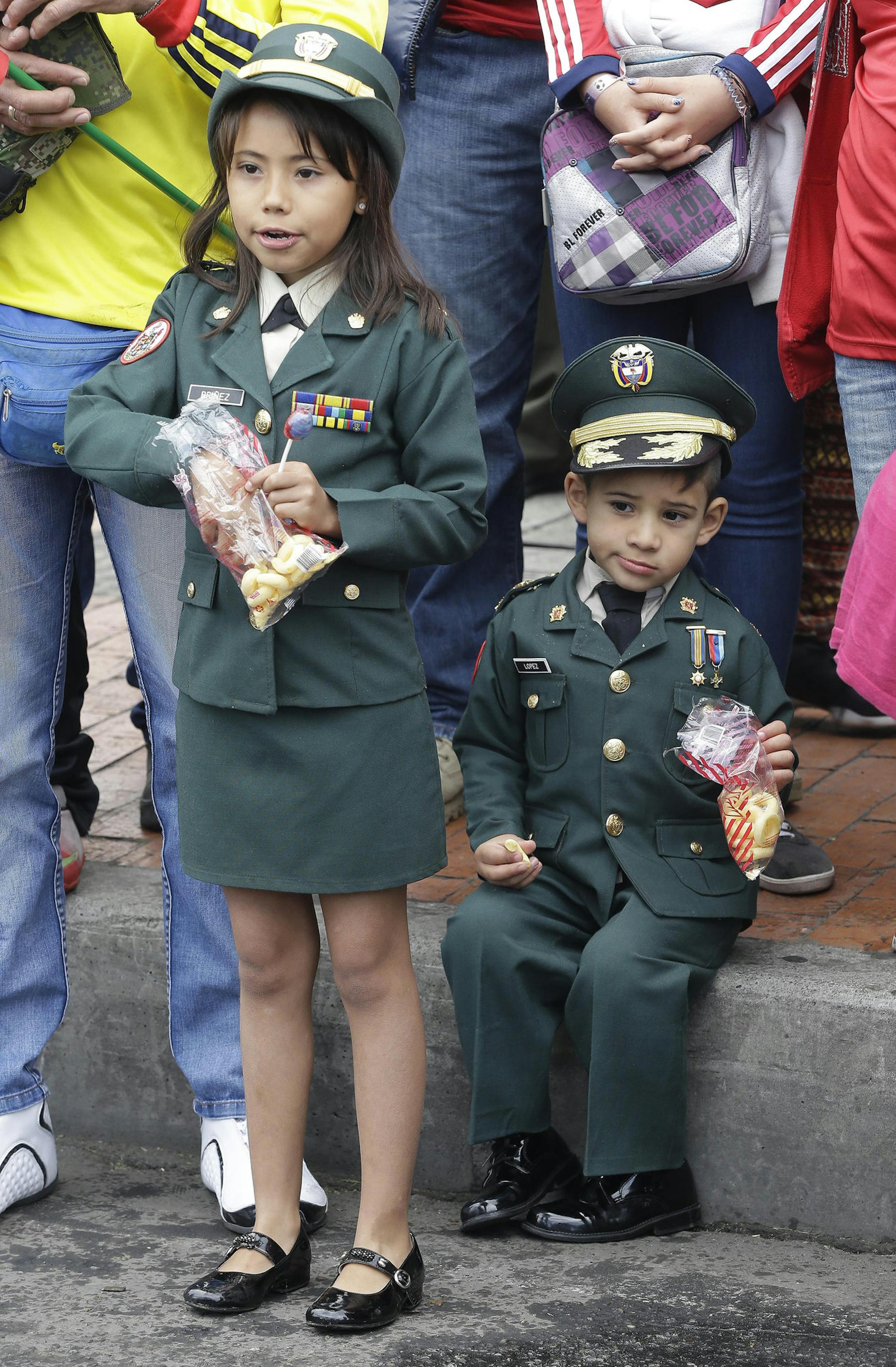 Children in military uniforms eat their snacks as the watch a military parade march by, during the marking Colombia's 204 anniversary of independence from Spain, in Bogota, Colombia, Sunday, July 20, 2014. (AP Photo/Fernando Vergara)