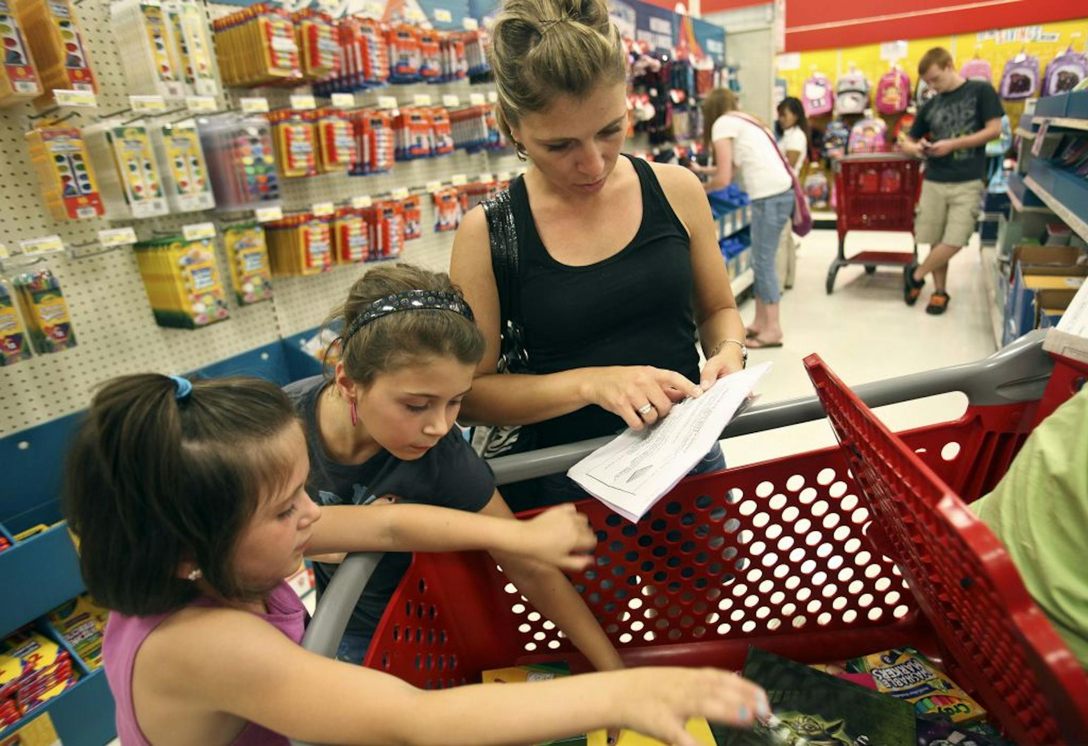 Christy Cook, of Bemidji, went over the lists of school supplies for her daughters, Chloe, 6, left, and Kenna, 7, as they shopped Wednesday at a Target store in Eden Prairie.