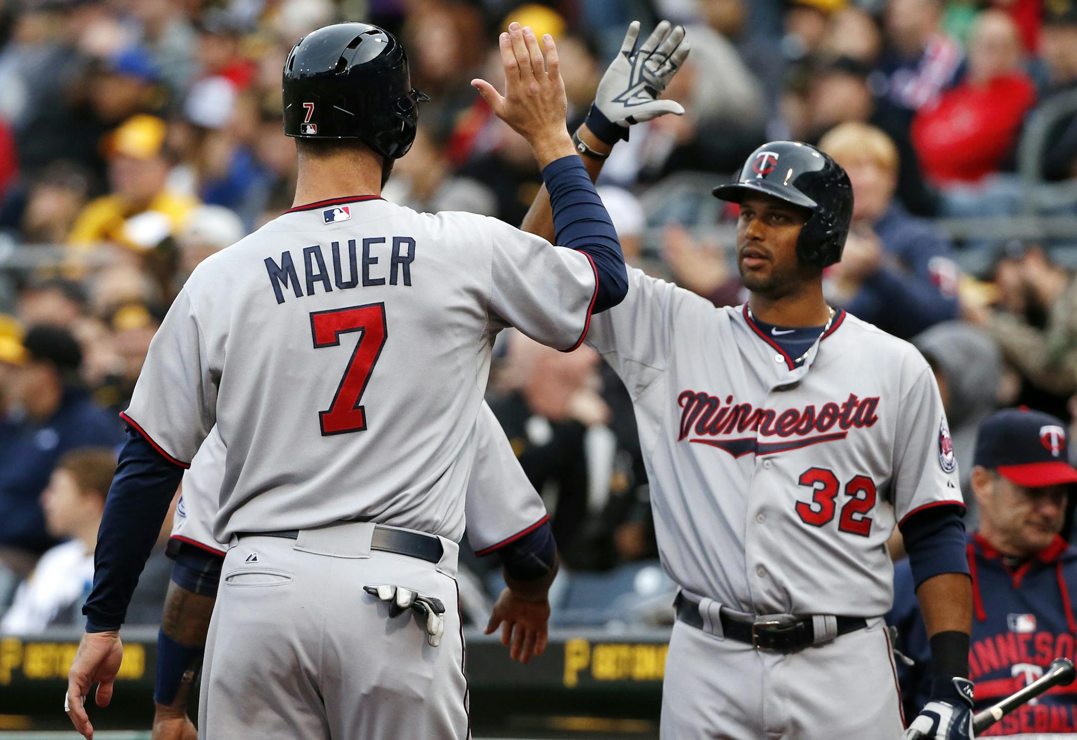 Minnesota Twins' Joe Mauer (7) is greeted by Aaron Hicks (32) after scoring on a three-run double by Torii Hunter off Pittsburgh Pirates starting pitcher Jeff Locke during the first inning of a baseball game in Pittsburgh, Wednesday, May 20, 2015. (AP Photo/Gene J. Puskar)