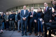 Trooper Ryan Londregan, center in maroon tie, stood hand in hand with his wife surrounded by security, his lawyers and dozens of supporters, including