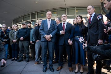 Trooper Ryan Londregan, center in maroon tie, stood hand in hand with his wife surrounded by security, his lawyers and dozens of supporters, including