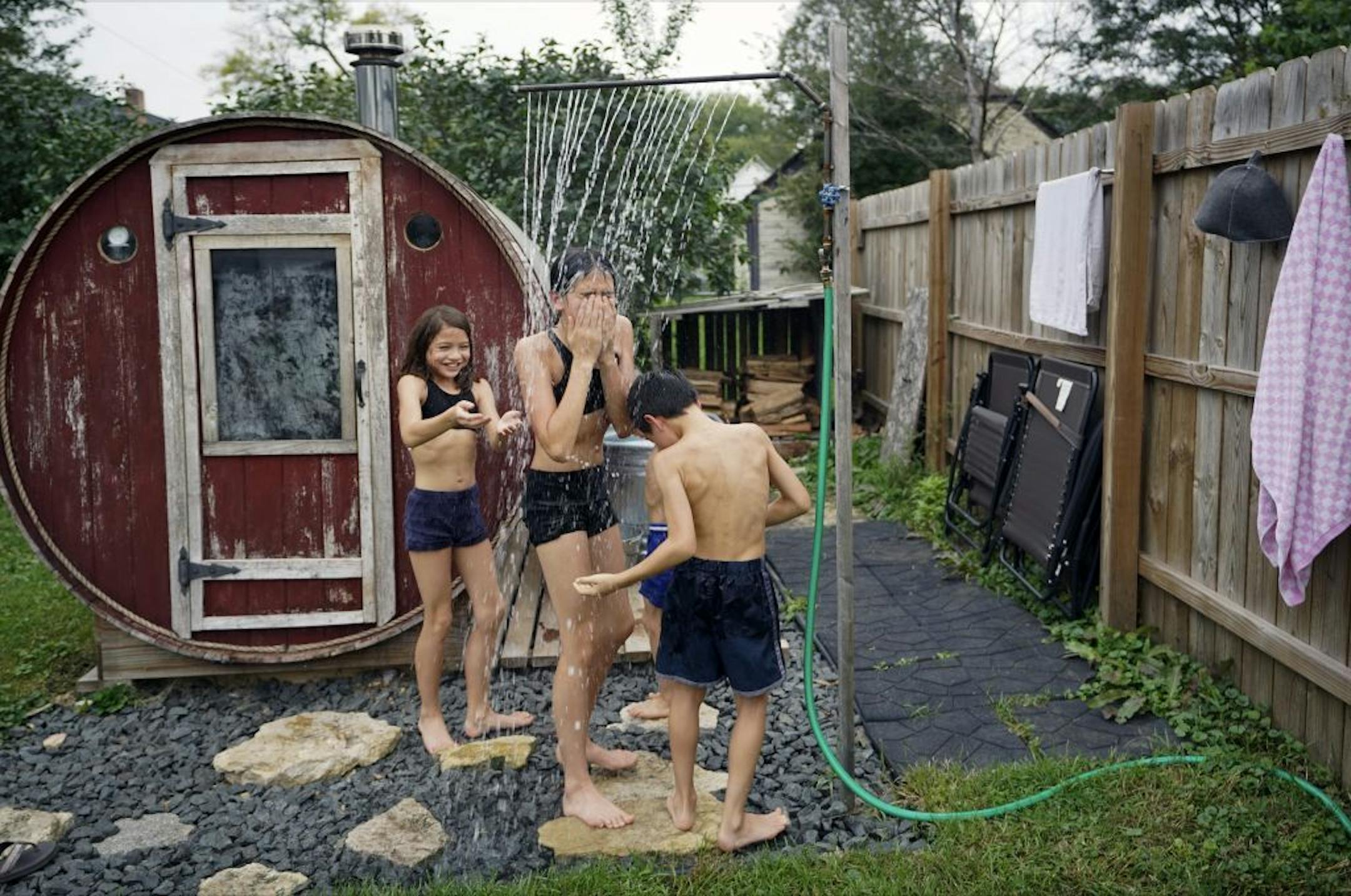 The Rice children, Nahlah, 10, Becca, 12, and Hudson, 8, take a quick cool down shower after a round in the barrel sauna.