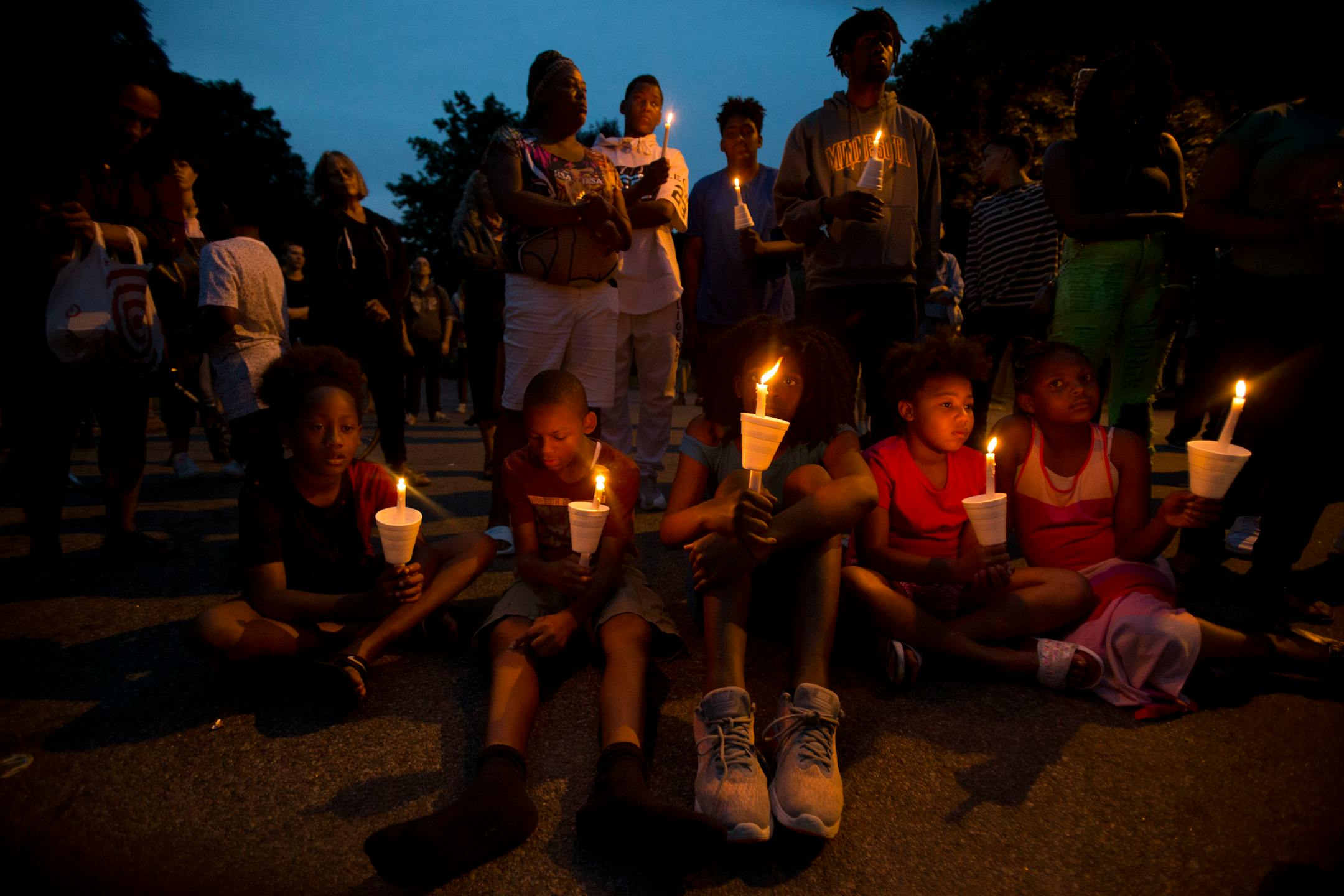 (From left) Christian Young, Damarion Sims, Emahnie Griffin, Sonia Young and Nieyhema Griffin sit on the street holding candles as dusk falls on the vigil Sunday night . ] ALEX KORMANN � alex.kormann@startribune.com Dozens of local community members, family of Thurman Belvins and activists gathered at the corner of 48th street and Camden Ave on Sunday evening for a candle lit vigil to remember the life of Belvins who died Saturday. Belvins was shot by police starting on that same corner Saturday