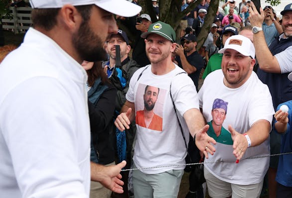 Scottie Scheffler, left, shakes hands with fans wearing Scottie Scheffler T-shirts as he walks off the ninth green during the second round of the PGA 