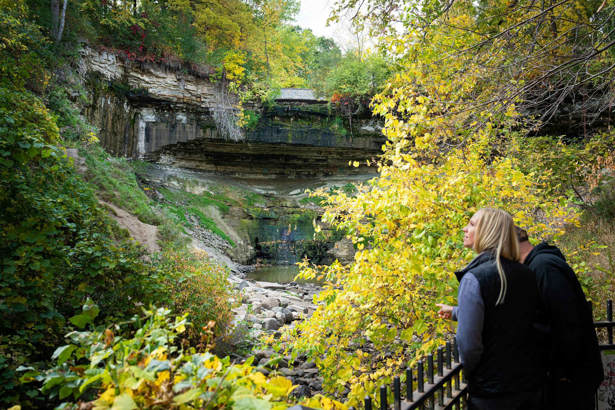 People look at a dried up Minnehaha Creek near Minnehaha Falls in Minneapolis.