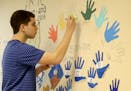 International Baccalaureate Hebrew program junior Sam Orloff paints his hand print on the classroom wall as part of an annual rite of passage for juni