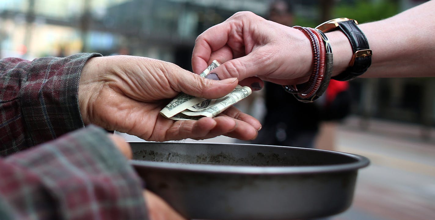 Edwin Schall got a dollar from a passerby as he held out a pan t get money for food along Nicollet Ave. ] (KYNDELL HARKNESS/STAR TRIBUNE) kyndell.harkness@startribune.com In downtown Minneapolis, Min. Tuesday, June 3, 2014. A new campaign in Minneapolis wants to end panhandling. The "Give Real Change Campaign" which has billboards in Downtown Minneapolis, is telling residents to end panhandling and give to a charitable organization instead. ORG XMIT: MIN1406031618130714