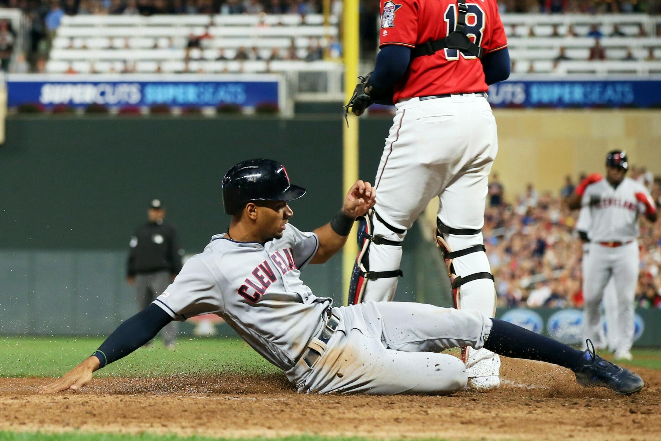 Cleveland's Oscar Mercado slides safely into home to score on a sacrifice fly by Yasiel Puig against the Twins to tie the score during the eighth inning
