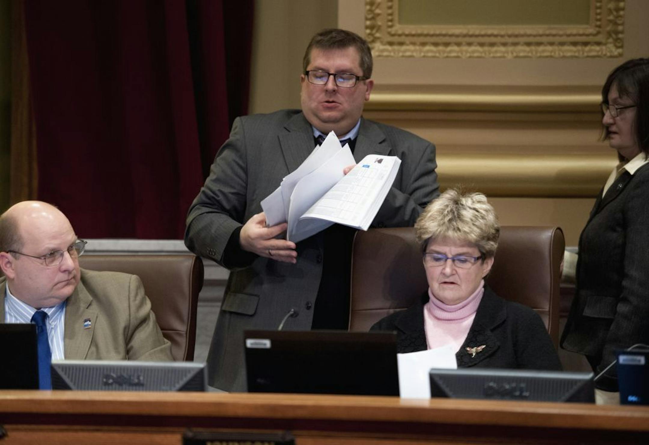 Minneapolis city clerk Casey Carl quickly distributed spreadsheets that contained long-awaited figures on expenses at the Minneapolis Convention Center that would be part of the stadium package as Mayor R.T. Rybak presented the latest stadium proposal to the city council Thursday, January 26, 2012. On the left is council member John Quincy, on the right council president Barbara Johnson and Sandy Colvin Roy