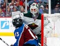 Minnesota Wild goaltender Devan Dubnyk, back, pushes Colorado Avalanche center Alexander Kerfoot out of the crease during the third period of an NHL h