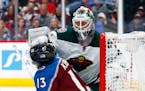Minnesota Wild goaltender Devan Dubnyk, back, pushes Colorado Avalanche center Alexander Kerfoot out of the crease during the third period of an NHL h