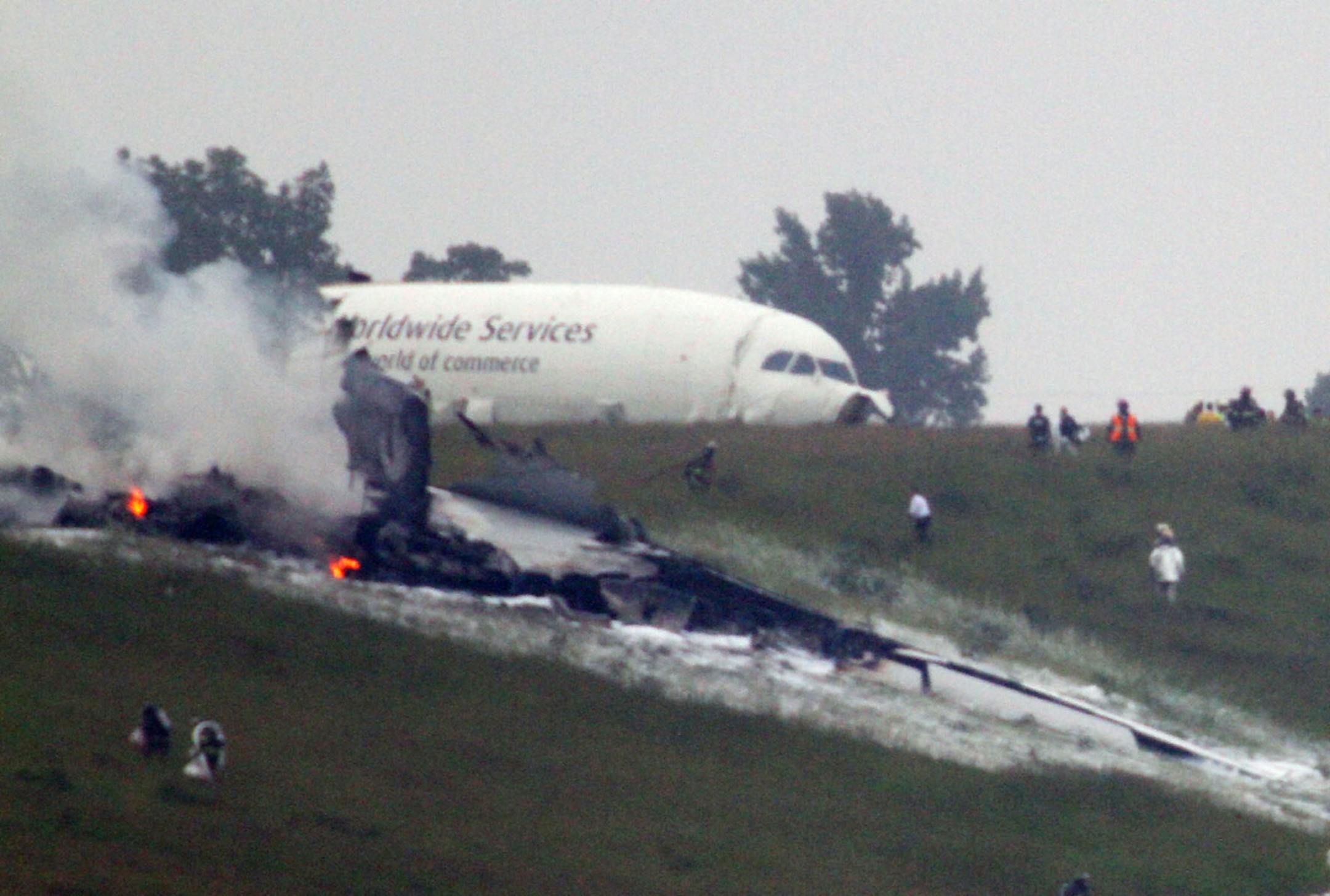 Debris burns as a UPS cargo plane lies on a hill at Birmingham-Shuttlesworth International Airport after crashing on approach, Wednesday, Aug. 14, 2013, in Birmingham, Ala.