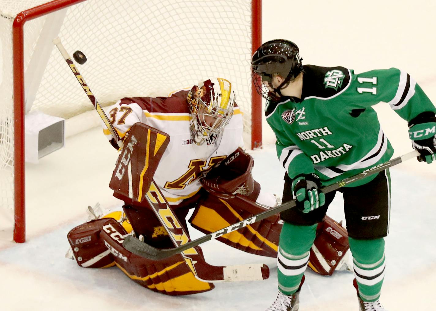 University of Minnesota goalie Eric Schierhorn (37) makes a save on a second period shot as the North Dakota's Trevor Olson (11) circles the goal