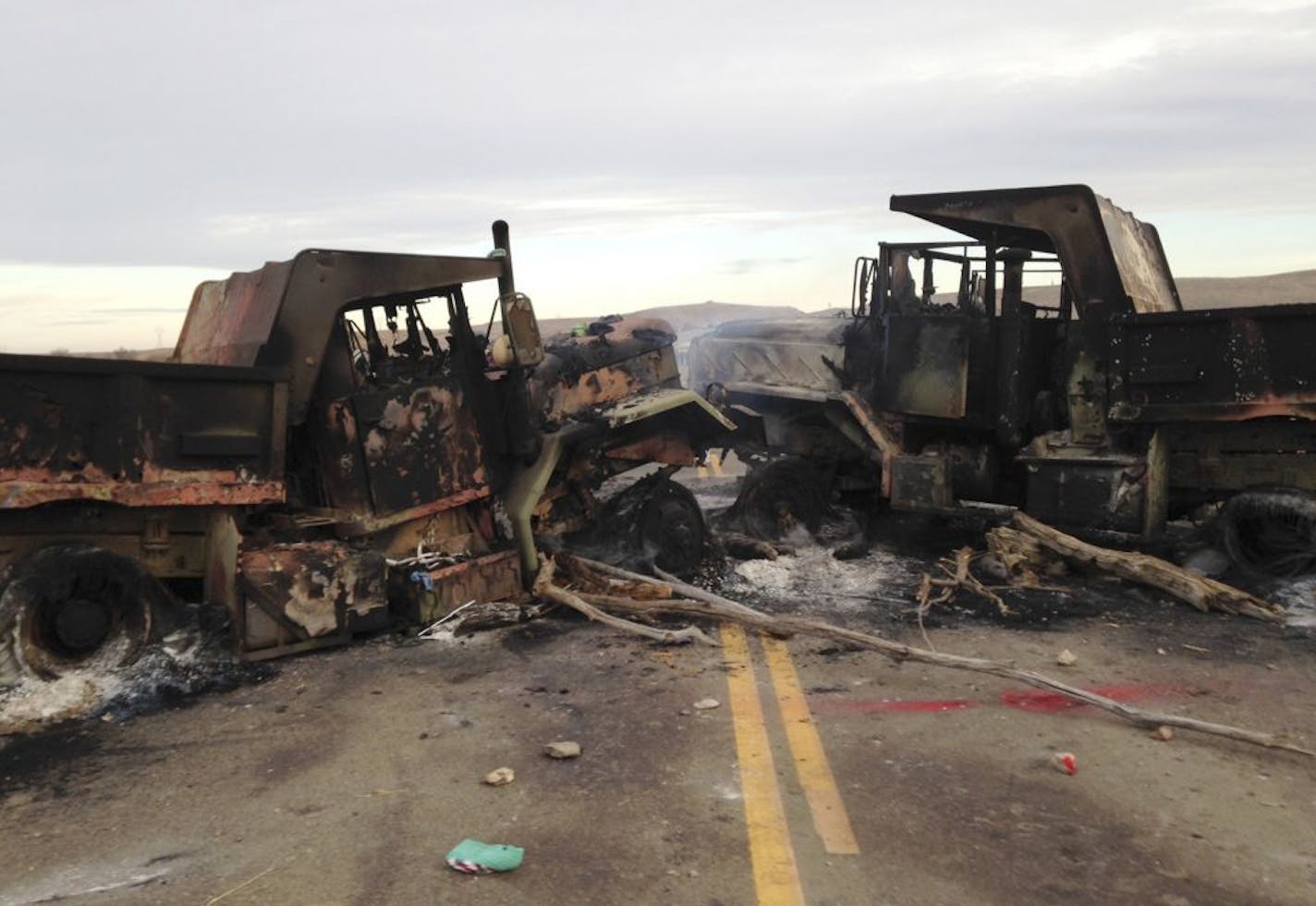 The burned hulks of heavy trucks, which authorities say were set afire by Dakota Access pipeline protesters, sit on Hwy. 1806 near Cannon Ball, N.D., on Friday.