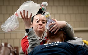 Kennedy Carlson keeps a supply of oxygen going for a manikin as part of a fast-tracked paramedics course held at Anoka Technical College on Wednesday,