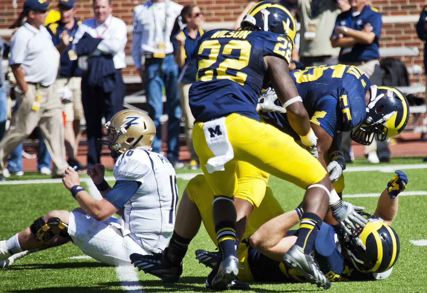 Akron quarterback Kyle Pohl, left, sits on the field as Michigan safety Jarrod Wilson (22) and defensive tackle Jibreel Black (55) celebrate with linebacker Brennen Beyer, bottom, their defensive stop on Akron's fourth down conversion attempt in the closing second of the fourth quarter of an NCAA college football game in Ann Arbor, Mich., Saturday, Sept. 14, 2013. Michigan won 28-24. (AP Photo/Tony Ding)