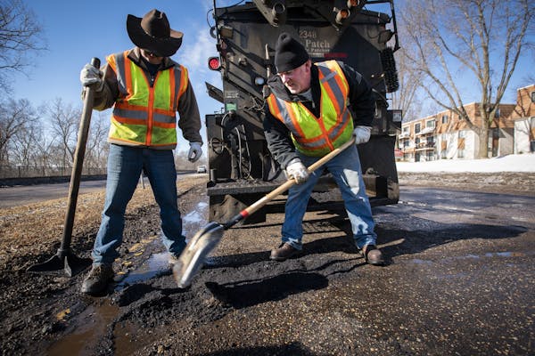 Street service workers Bradley Therres, left, and Lance Hamby fill potholes on Shepard Road.