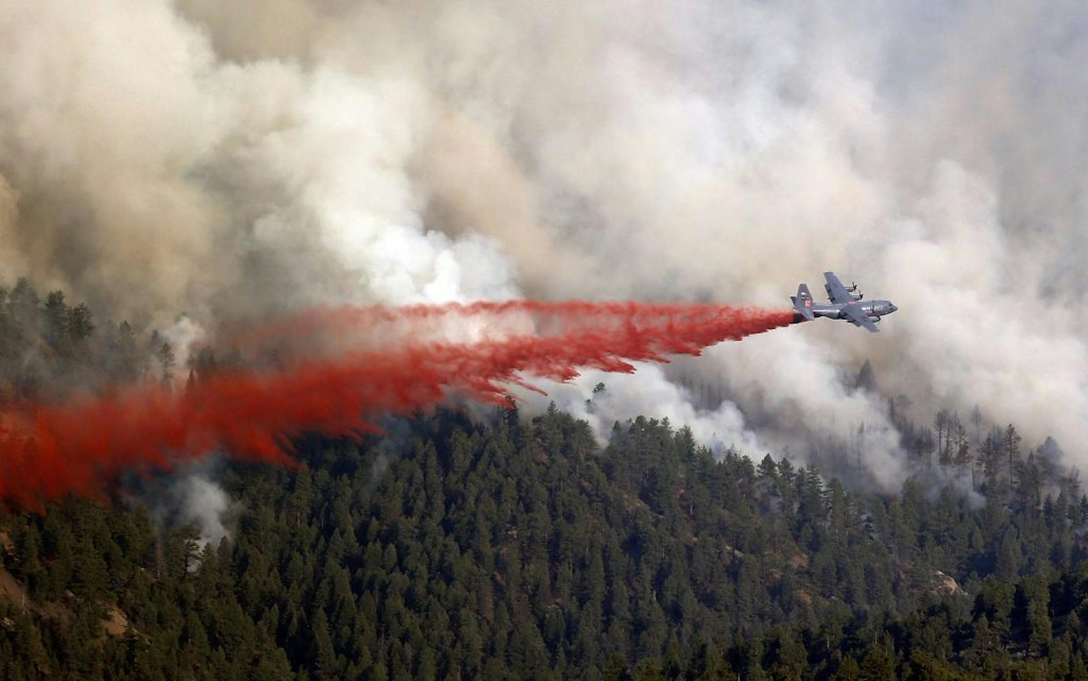 A military C-130 drops a load of fire retardant on a wildfire near Pine, Colo., on Wednesday, June 19, 2013. A new wildfire in the foothills southwest of Denver forced the evacuation of dozens of homes Wednesday.