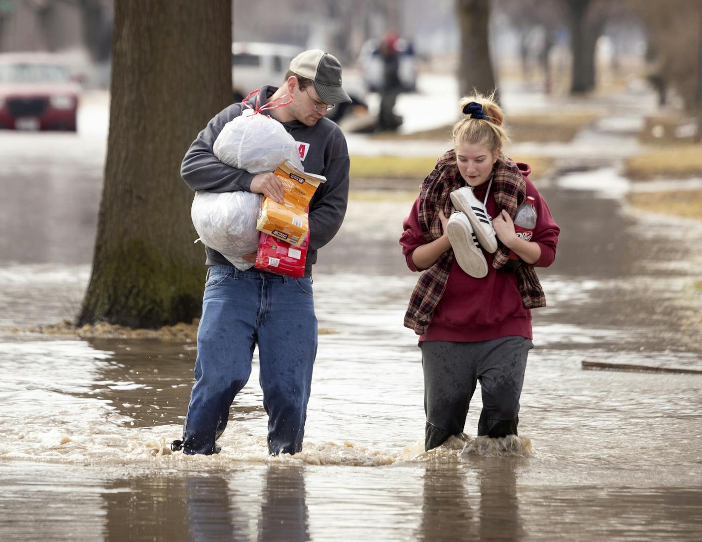 Anthony Thomson, left, and Melody Walton make their way out of a flooded neighborhood Sunday, May 17, 2019, in Fremont, Neb. Hundreds of people were evacuated from their homes in Nebraska and Iowa as levees succumbed to the rush of water. (Kent Sievers/Omaha World-Herald via AP)