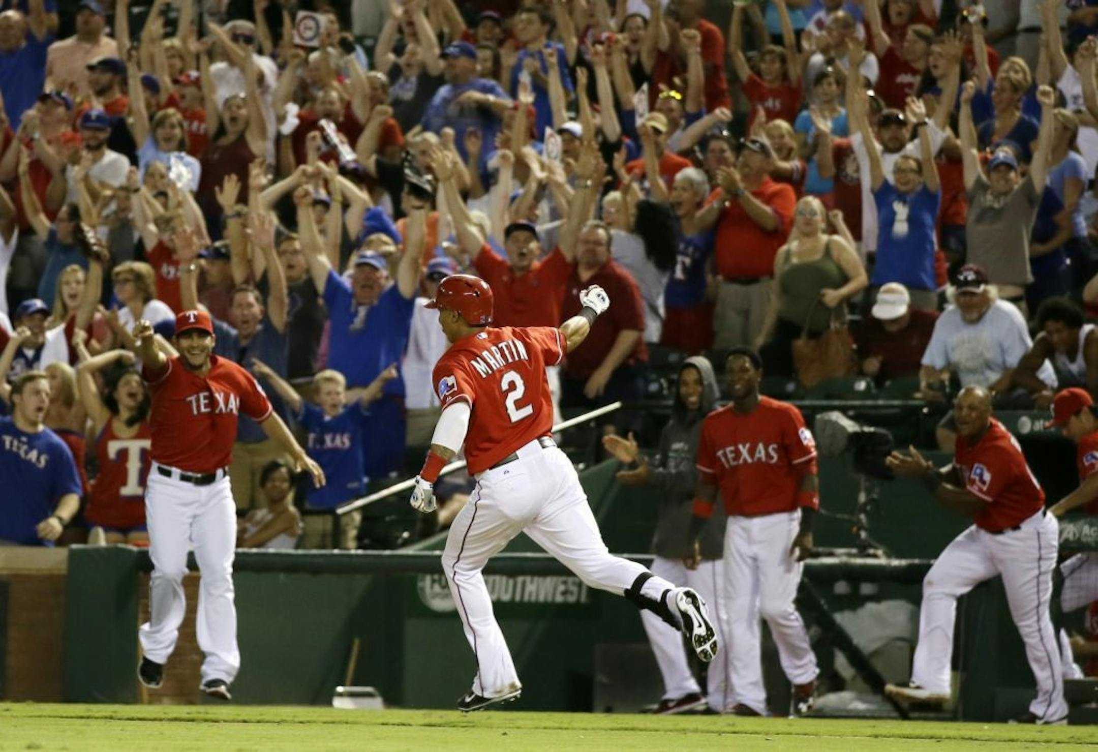 Texas Rangers' Leonys Martin (2) celebrates as players run out of the dugout after Martin hit a walk-off single that scored Alex Rios in the ninth inning of a baseball game against the Minnesota Twins, Saturday, Aug. 31, 2013, in Arlington, Texas. The hit came off a pitch from relief pitcher Josh Roenicke in the 2-1 Rangers win.