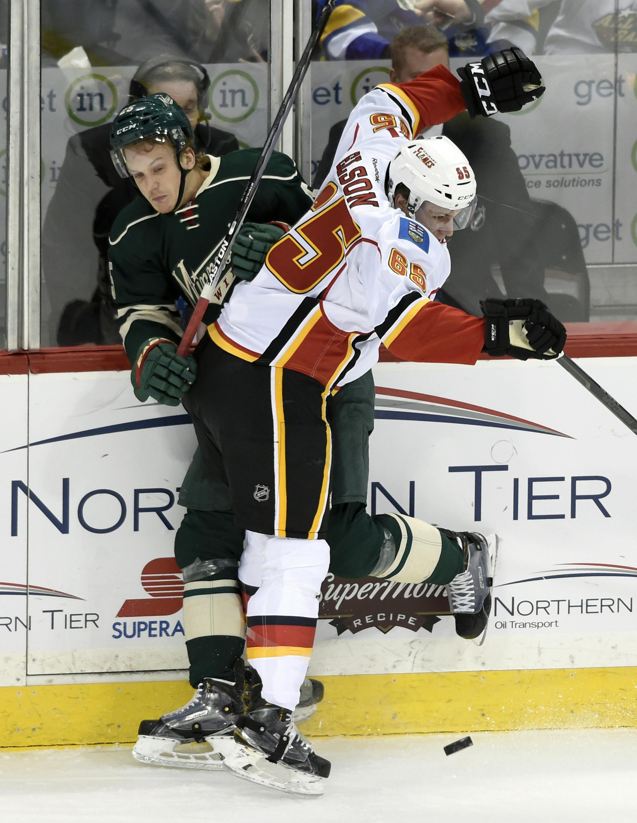 Calgary Flames' Turner Elson (65) checks Minnesota Wild's Jonas Brodin, of Sweden, during the first period of an NHL hockey game Saturday, April 9, 2016, in St. Paul, Minn. (AP Photo/Hannah Foslien)