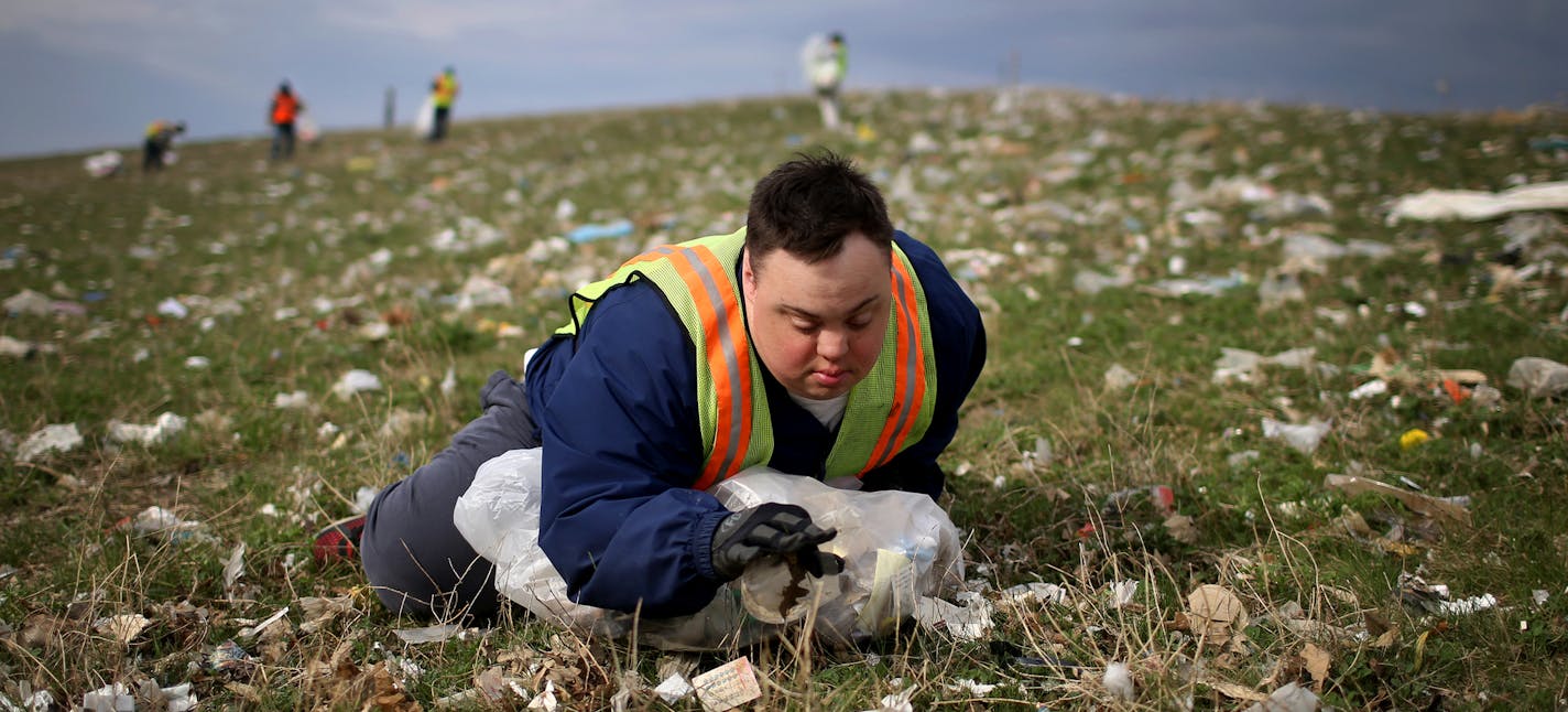 Scott Rhude, 33, sits spread-eagled in a field of garbage, reaching for a piece of trash while on a work assignment with a sheltered workshop "enclave" Tuesday, April 28, 2015, near the landfill in Wilmar, MN. Like many of his coworkers on the cleanup crew, Rhude dreams of landing a &#xec;real job&#xee; in the community. But for that, he would need specialized training, transportation to and from work and access to a job coach.&#xec;He is stuck, stuck stuck,&#xee; said Mary Rhude, Scott&#xed;s m