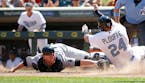 Minnesota Twins' Trevor Plouffe (24) is safe at home plate as he avoids the tag of New York Yankees catcher Brian McCann on a two-run triple by Twins'