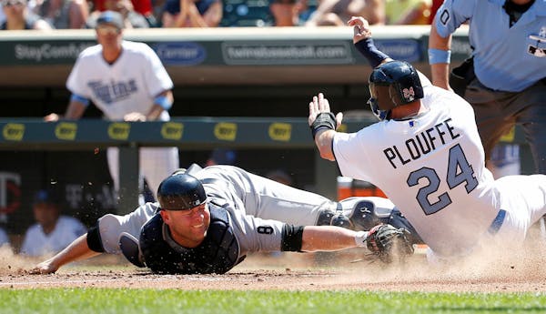 Minnesota Twins' Trevor Plouffe (24) is safe at home plate as he avoids the tag of New York Yankees catcher Brian McCann on a two-run triple by Twins'