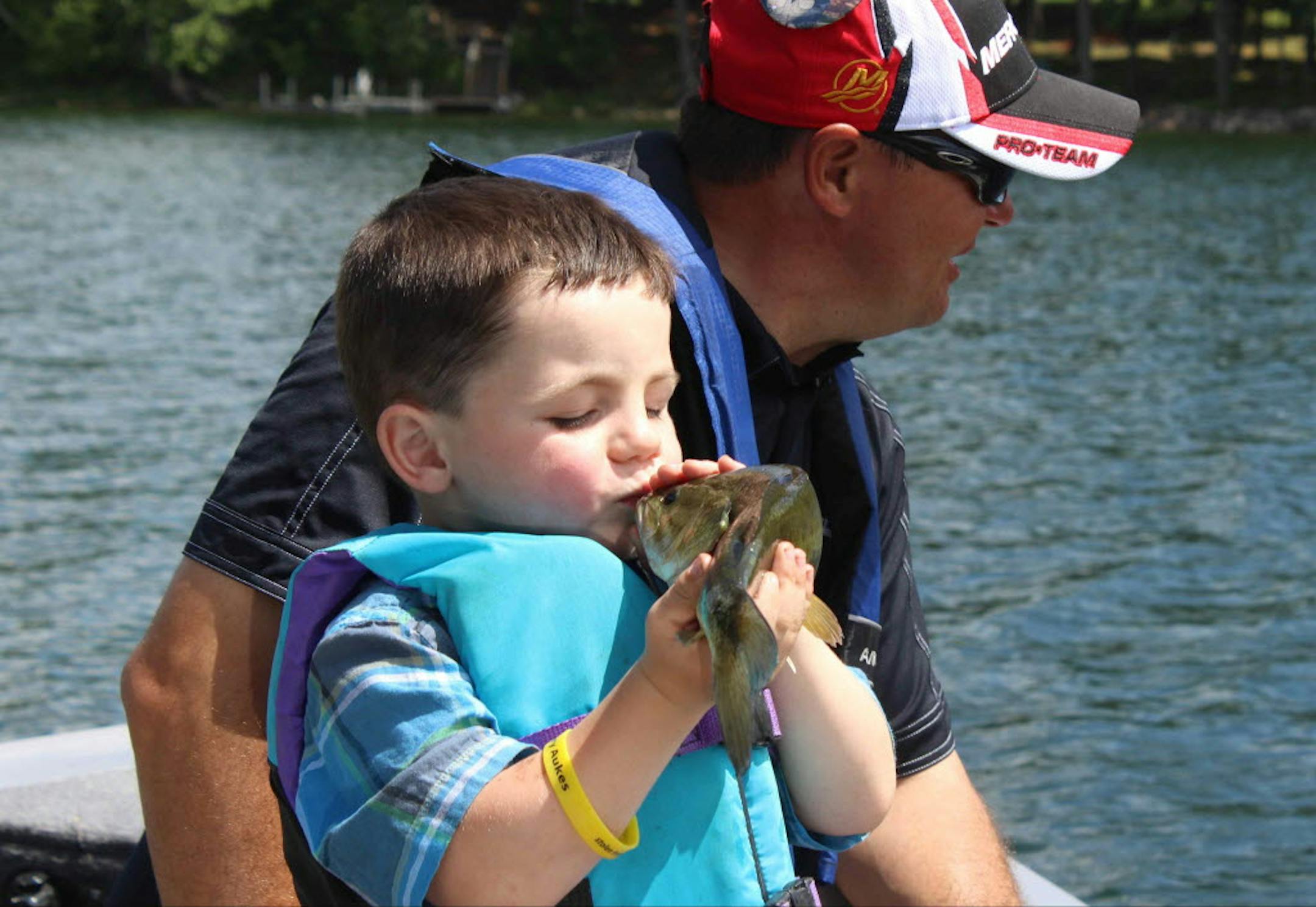 Bobby Tufts, the 4-year-old mayor of Dorset, Minn., kisses a fish that his guide, Jason Durham, caught on Lake Belle Taine.