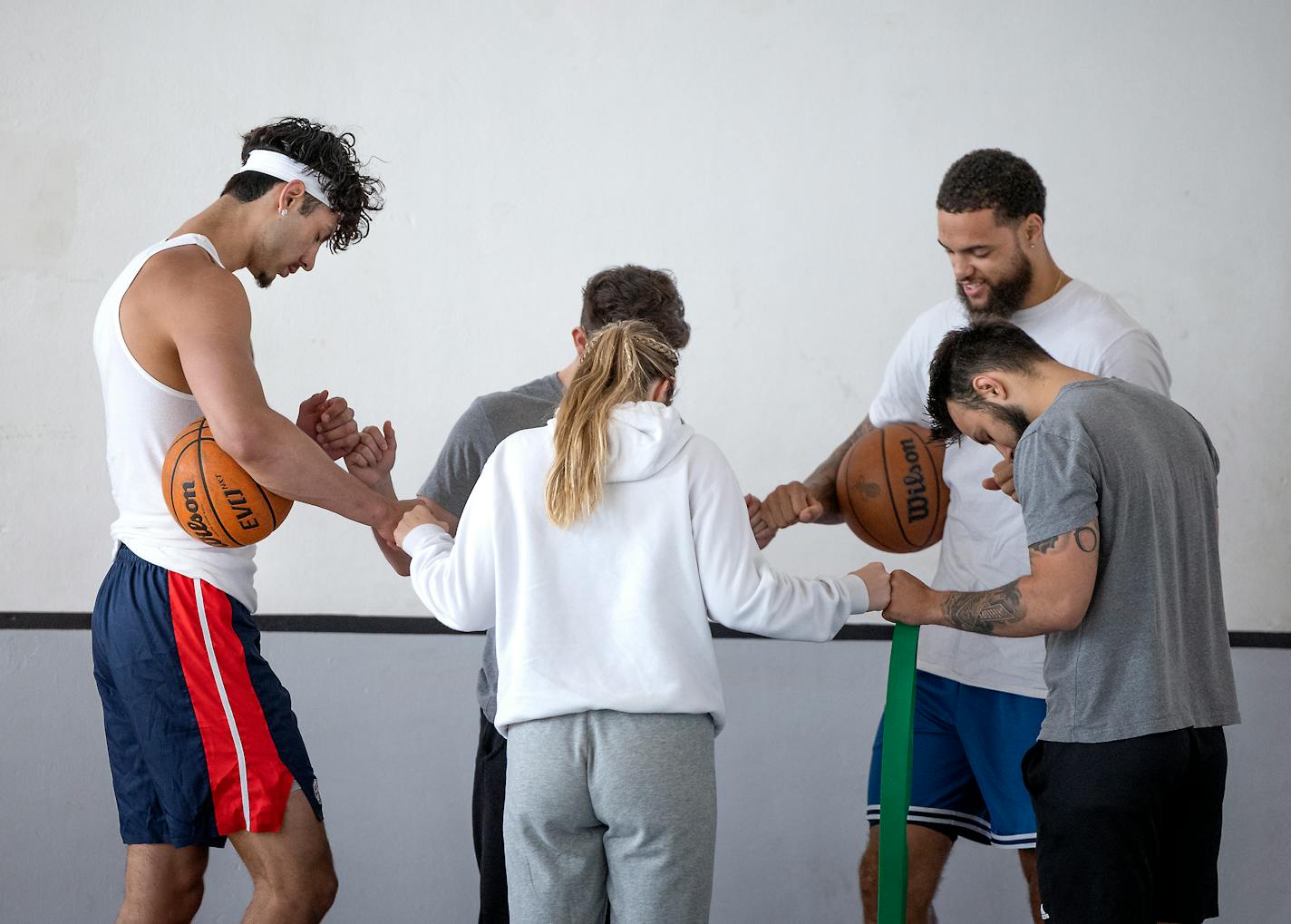 Dawson Garcia, left, joins hands in prayer with from left, Garcia, Griffin Trull, former Duke player Theo John, Dolan Tierney, and Betty Lou Rand, before practicing with the "Hoops and Christ" training team at a North Minneapolis gym in Minneapolis, Minn., on Tuesday, May 24, 2022. ] Elizabeth Flores • liz.flores@startribune.com