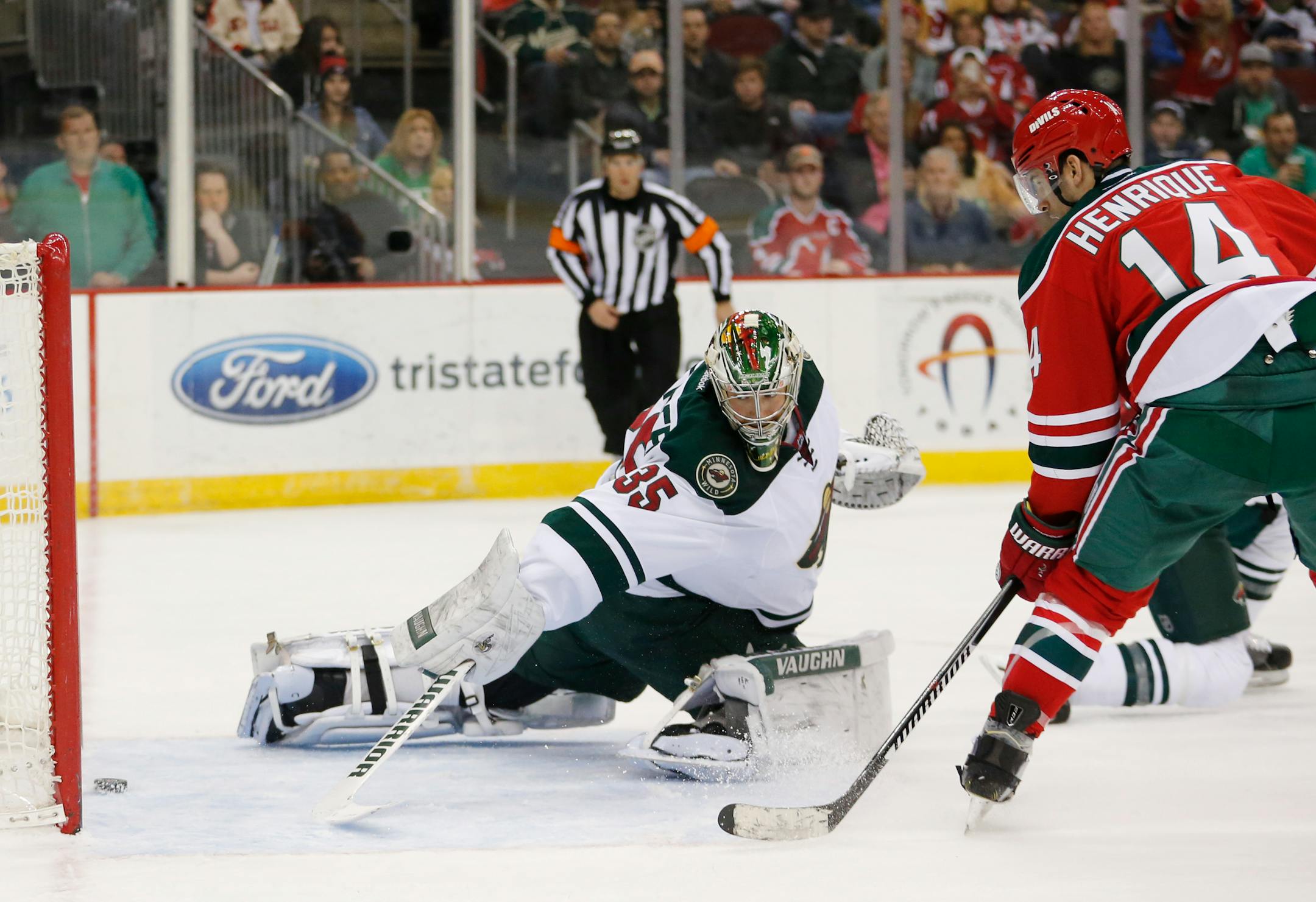 New Jersey Devils center Adam Henrique (14) scores a goal on Minnesota Wild goalie Darcy Kuemper (35) during the second period of an NHL hockey game, Thursday, March 17, 2016, in Newark, N.J. (AP Photo/Julio Cortez)