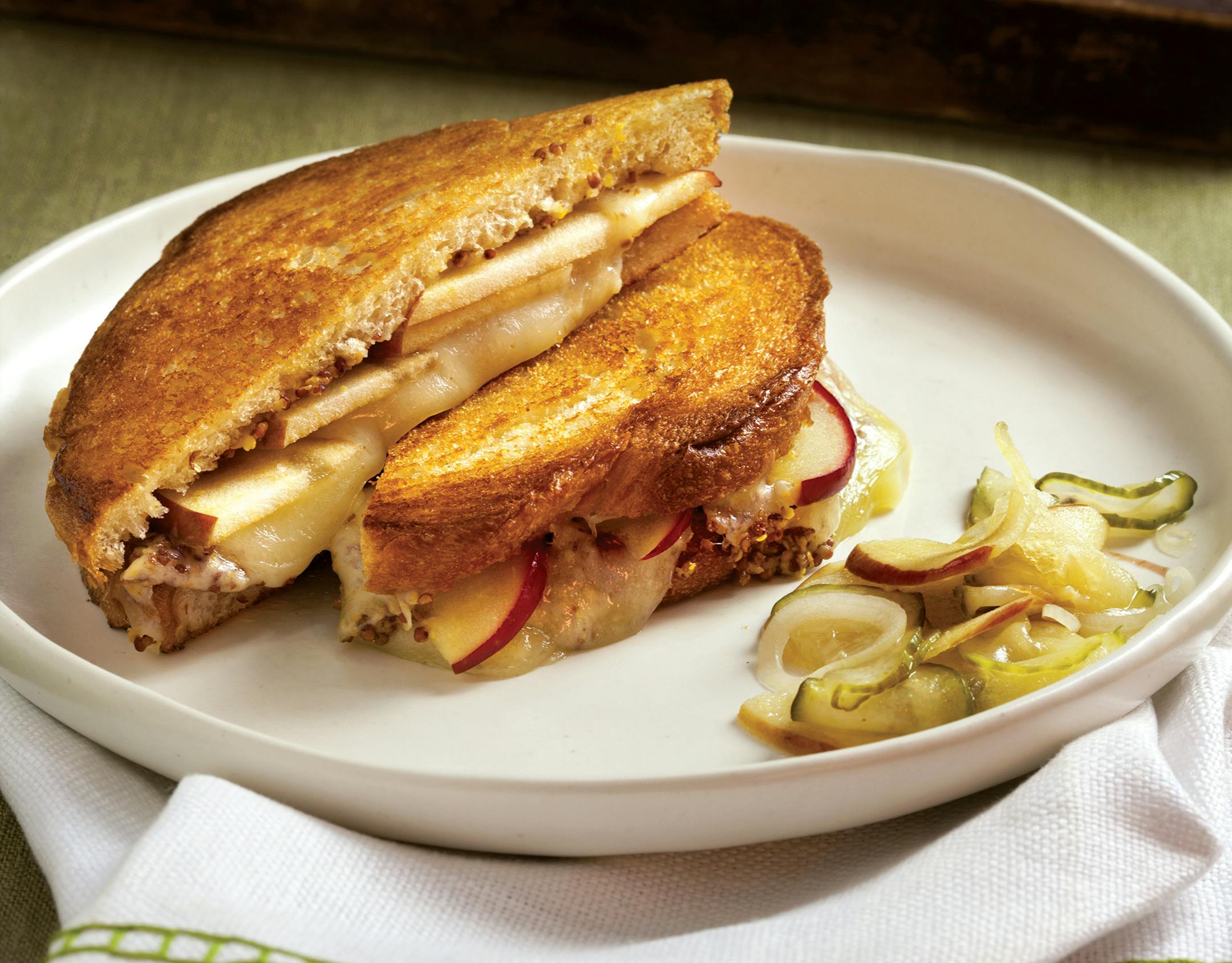 Photographs excerpted from The Apple Lover's Cookbook: Updated and Revised by Amy Traverso. Copyright (c) 2020 by Amy Traverso. Photographs copyright 2011 by Squire Fox. Used with permission of the publisher, W. W. Norton & Company, Inc. All rights reserved. Apple and Mustard Grilled Cheese with bread-and-butter apple pickes.