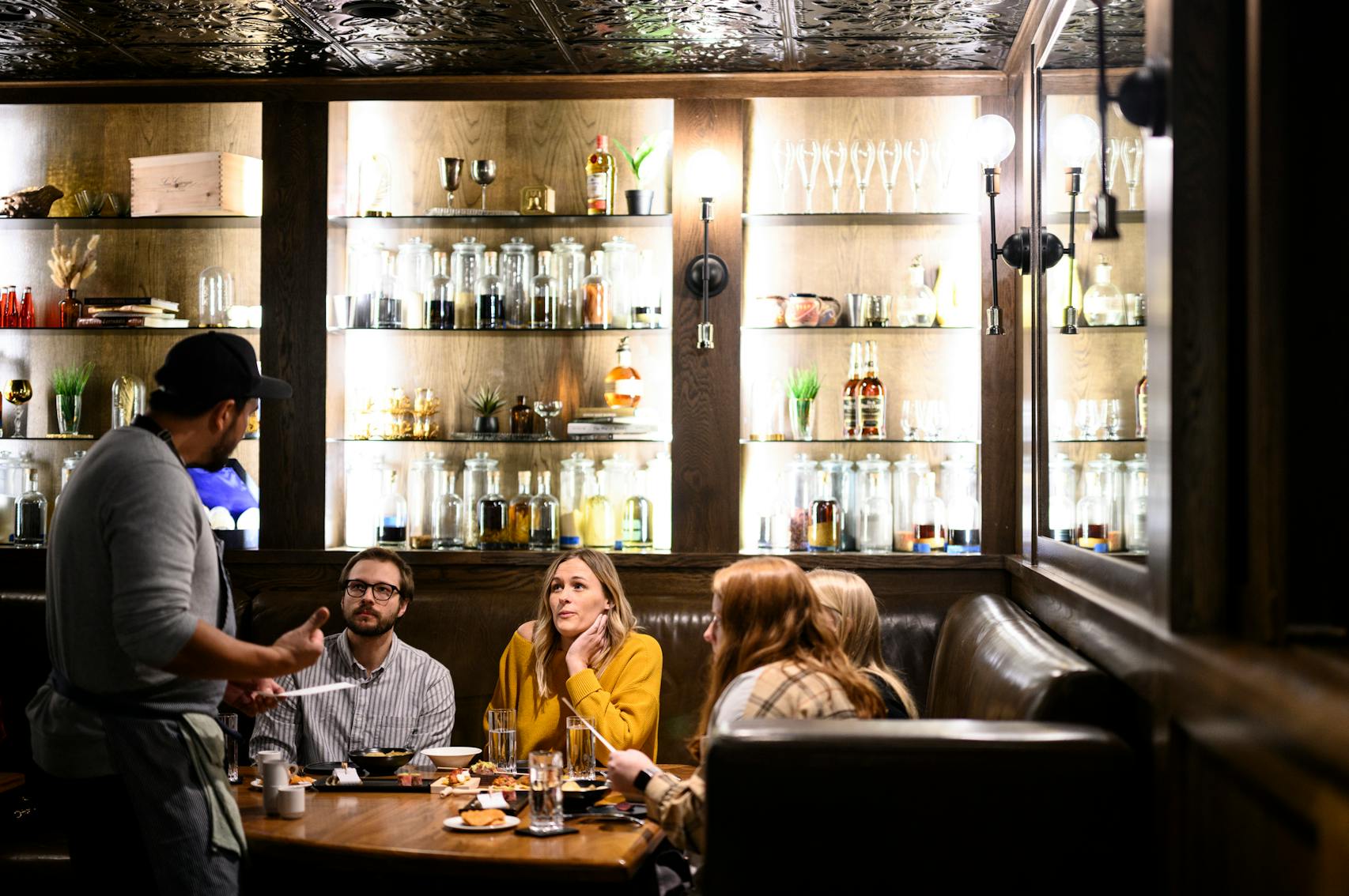 Travail co-owner Bob Gerken, left, speaks with patrons, from left, Jack Sturtz, Morgan Stadheim, Britta Rinke and Julia Sieling as they enjoy their first bites in the Basement Bar Wednesday, Feb. 16, 2022 at Travail Kitchen and Amusements in Robbinsdale, Minn. ] AARON LAVINSKY • aaron.lavinsky@startribune.com