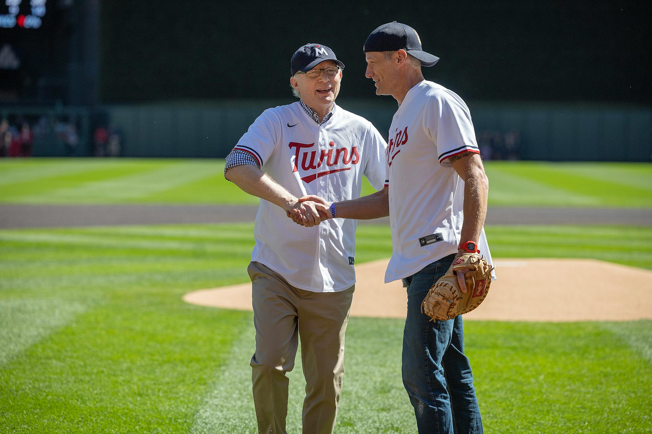 Retiring Star Tribune publisher Mike Klingensmith shakes hands with incoming publisher Steve Grove after he threw him the ceremonial first pitch.