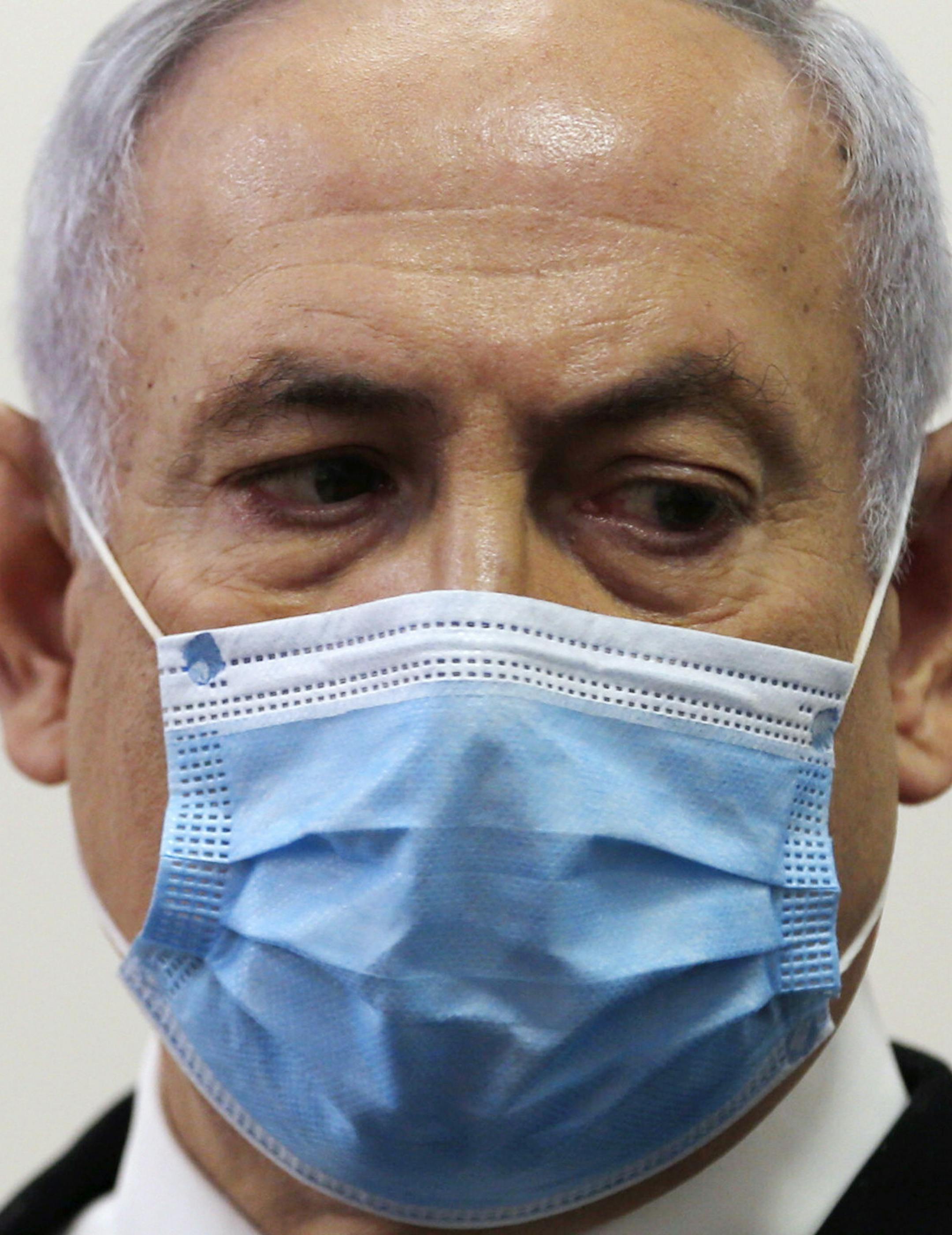 Israeli Prime Minister Benjamin Netanyahu, wearing a face mask in line with public health restrictions due to the coronavirus pandemic, looks at his lawyer inside the court room as his corruption trial opens at the Jerusalem District Court, Sunday, May 24, 2020. He is the country's first sitting prime minister ever to go on trial, facing charges of fraud, breach of trust, and accepting bribes in a series of corruption cases stemming from ties to wealthy friends. (Ronen Zvulun/ Pool Photo via AP)