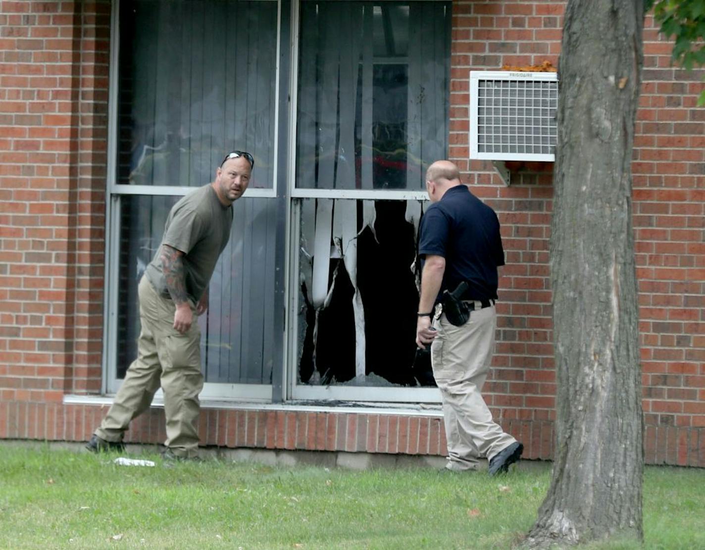 Investigators look over a broken window after an explosion Saturday at the Dar Al Farooq Islamic Center in Bloomington.