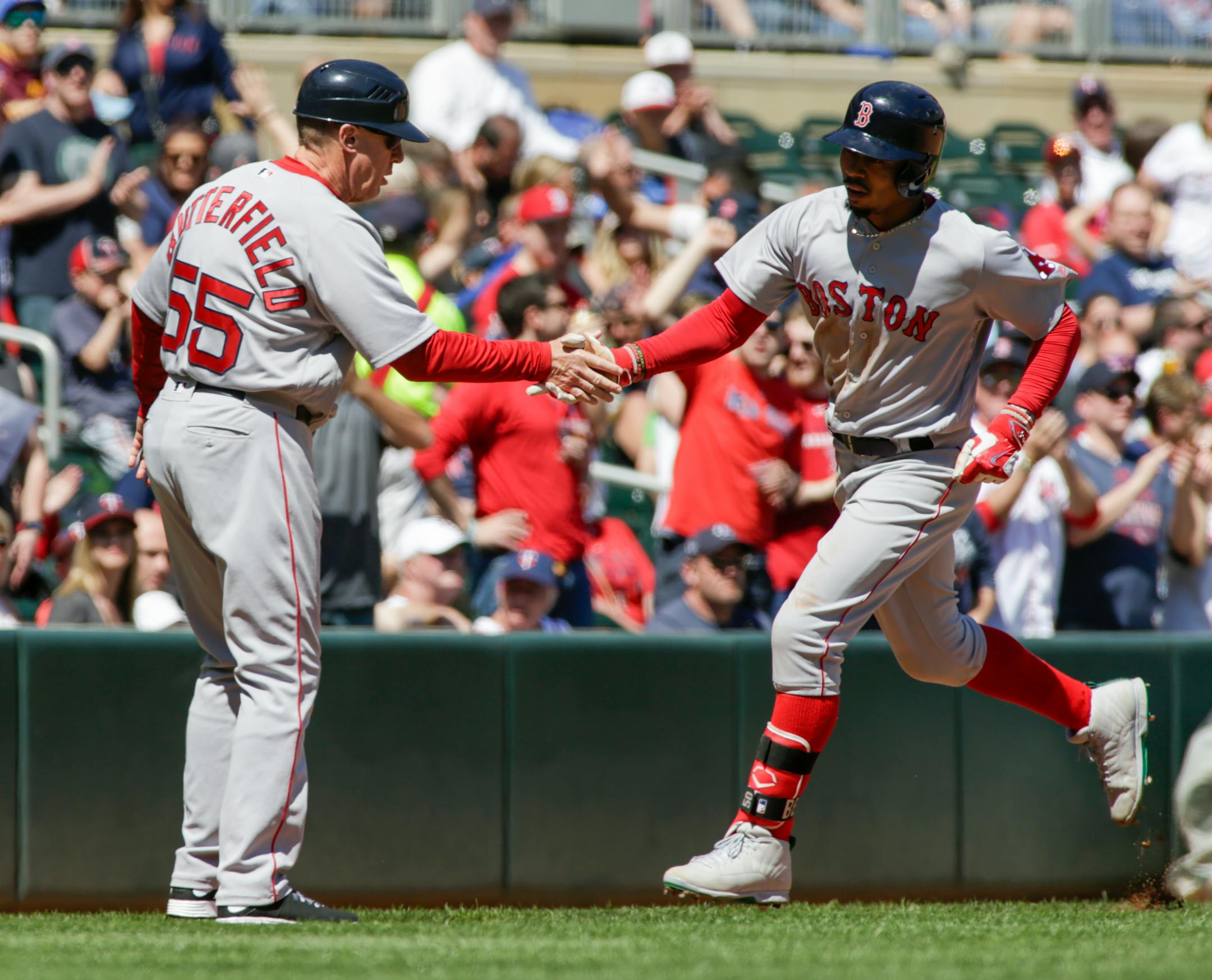 Boston Red Sox's Mookie Betts, right, is congratulated by third base coach Brian Butterfield after hitting a solo home run during the fifth inning of a baseball game against the Minnesota Twins, Sunday, May 7, 2017, in Minneapolis. (AP Photo/Paul Battaglia)
