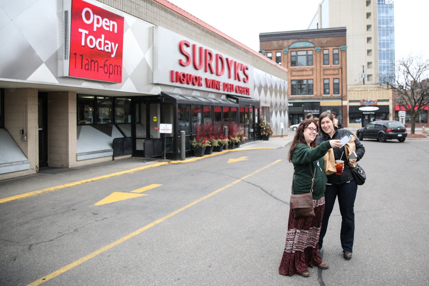 Nicole Larson, 30, and Lisa Gatzke, 33, take selfies in front of the opening liquor store on Sunday, March 12, 2017.