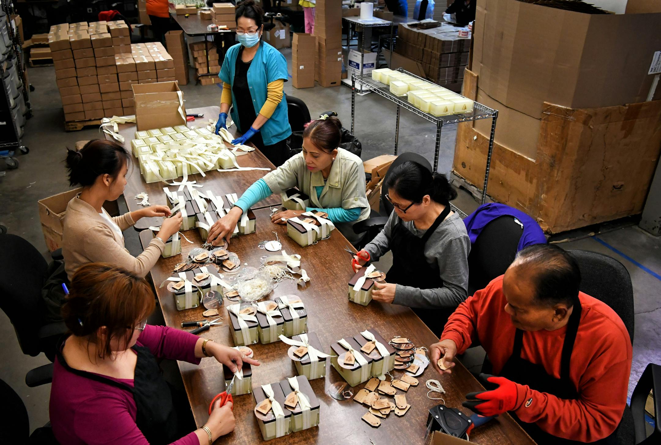 Workers put the finishing touches of hand-tied bows and tags on Thymes Frasier Fir candles in the firm’s Minneapolis facility.