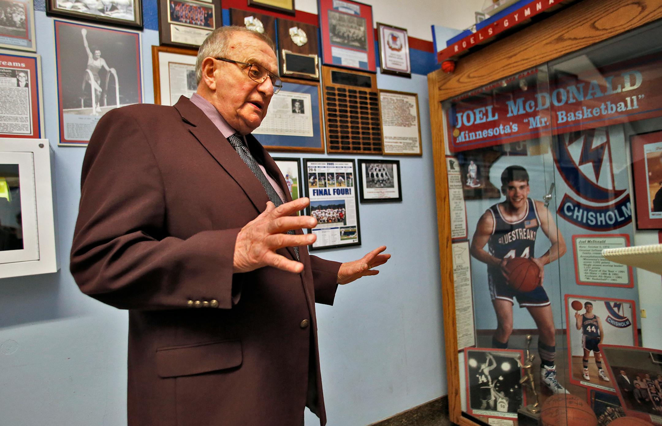 Coach Bob McDonald talked about some of the basketball trophies on display in the hallways of Chisholm High, including the display of his all-time scoring leader son Joel McDonald, right.