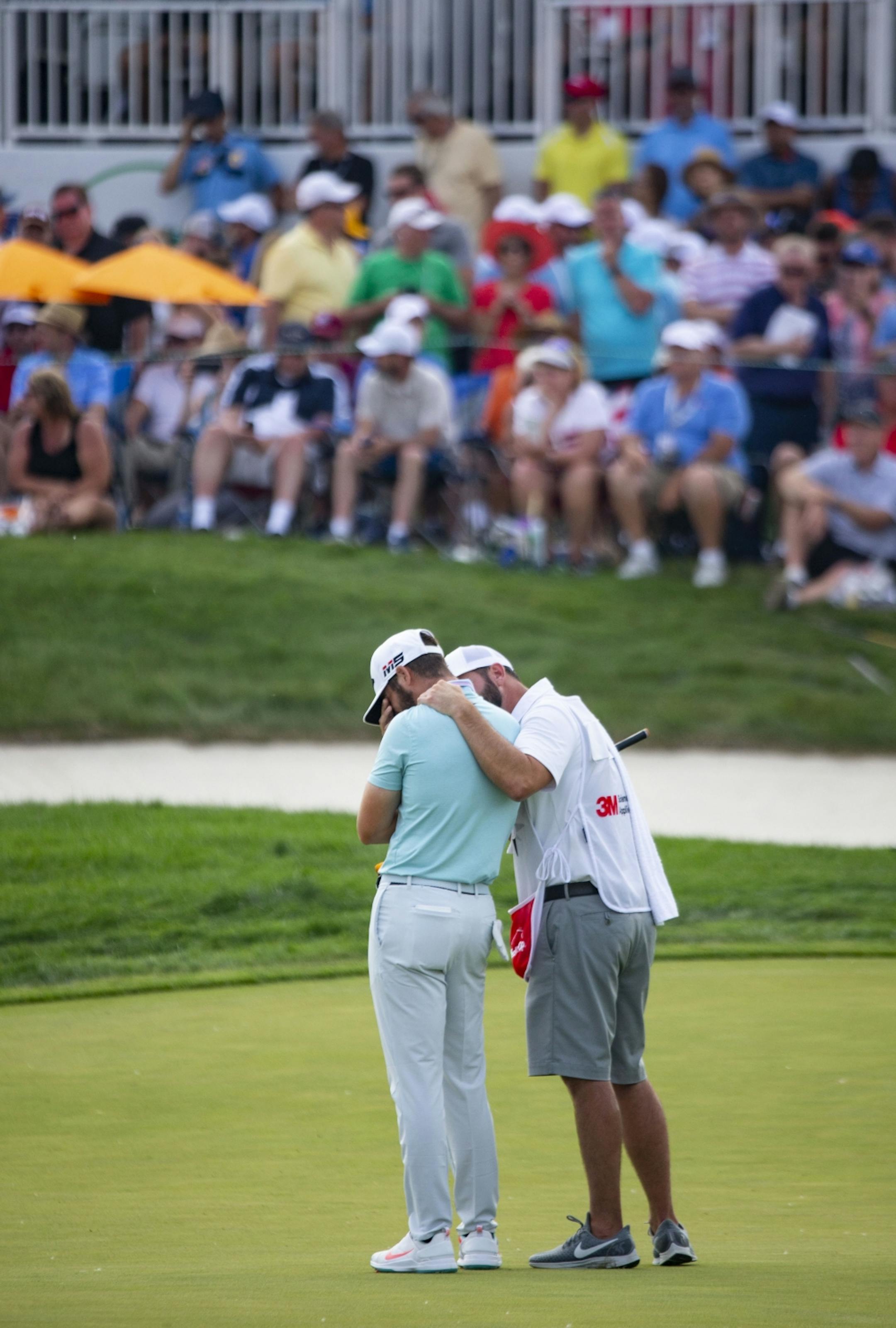 Matthew Wolff tears up while being held by his caddy after sinking an eagle putt on the 18th hole.