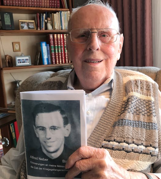 Alfred Neber, 95, who lives in Germany near Heidelberg, holds a photo of himself taken when he was about 20, around the time he was sent to work in Minnesota as a POW. 