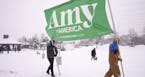Volunteers Tim Schumann, left, and Chase Cushman move an "Amy for America" sign into place Sunday, Feb. 10, 2019, prior to Democratic Sen. Amy Klobuch
