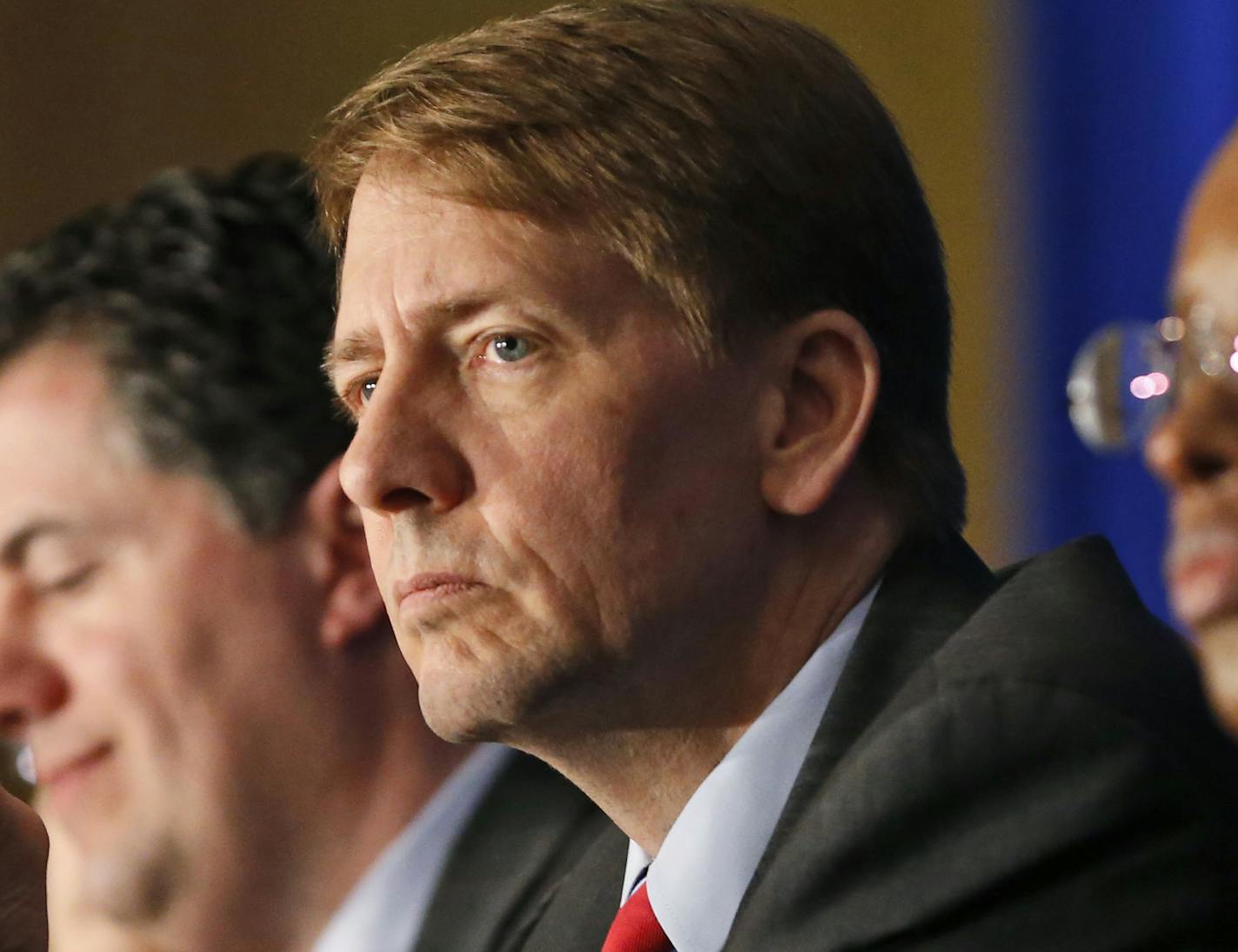 FILE - In this Thursday, March 26, 2015, file photo, Consumer Financial Protection Bureau Director Richard Cordray, center, listens to comments during a panel discussion in Richmond, Va. On Tuesday, Oct. 11, 2016, a federal appeals court ruled that the way the CFPB is organized violates the Constitution&#xed;s separation of powers by limiting the president&#xed;s ability to remove the director who heads the agency. Cordray, a Democrat and former Ohio attorney general, has run the agency since it