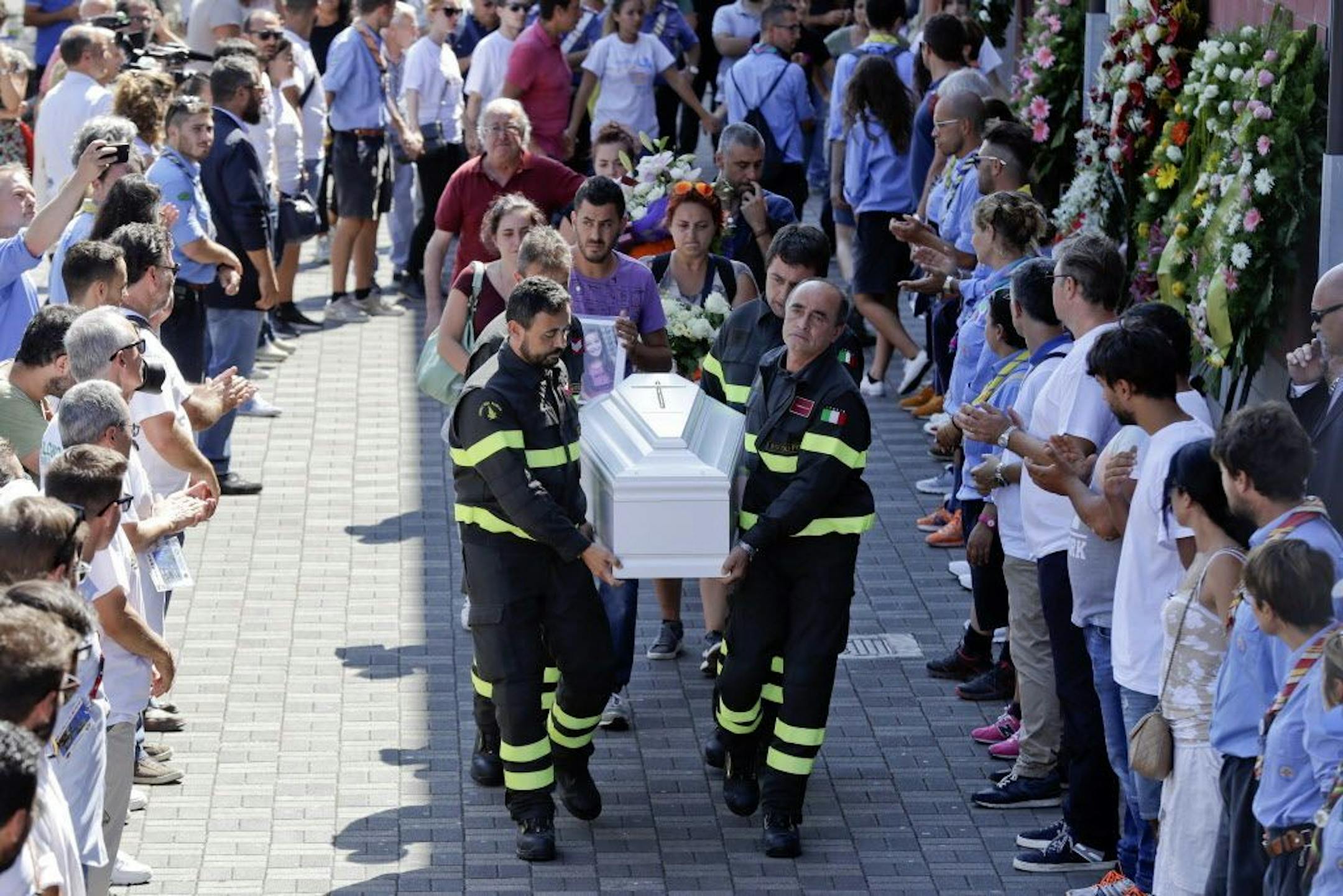 Firefighters carry the coffin of 9-year-old Giulia Rinaldo outside the gymnasium where a funeral service for some of the victims of the earthquake that hit central Italy last Wednesday took place, in Ascoli Piceno, Italy, Saturday, Aug. 27, 2016.